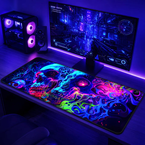 A gaming desk with a widescreen monitor, PC tower with purple LED fans, speaker, and a large mouse featuring neon skull artwork in a purple-lit room.